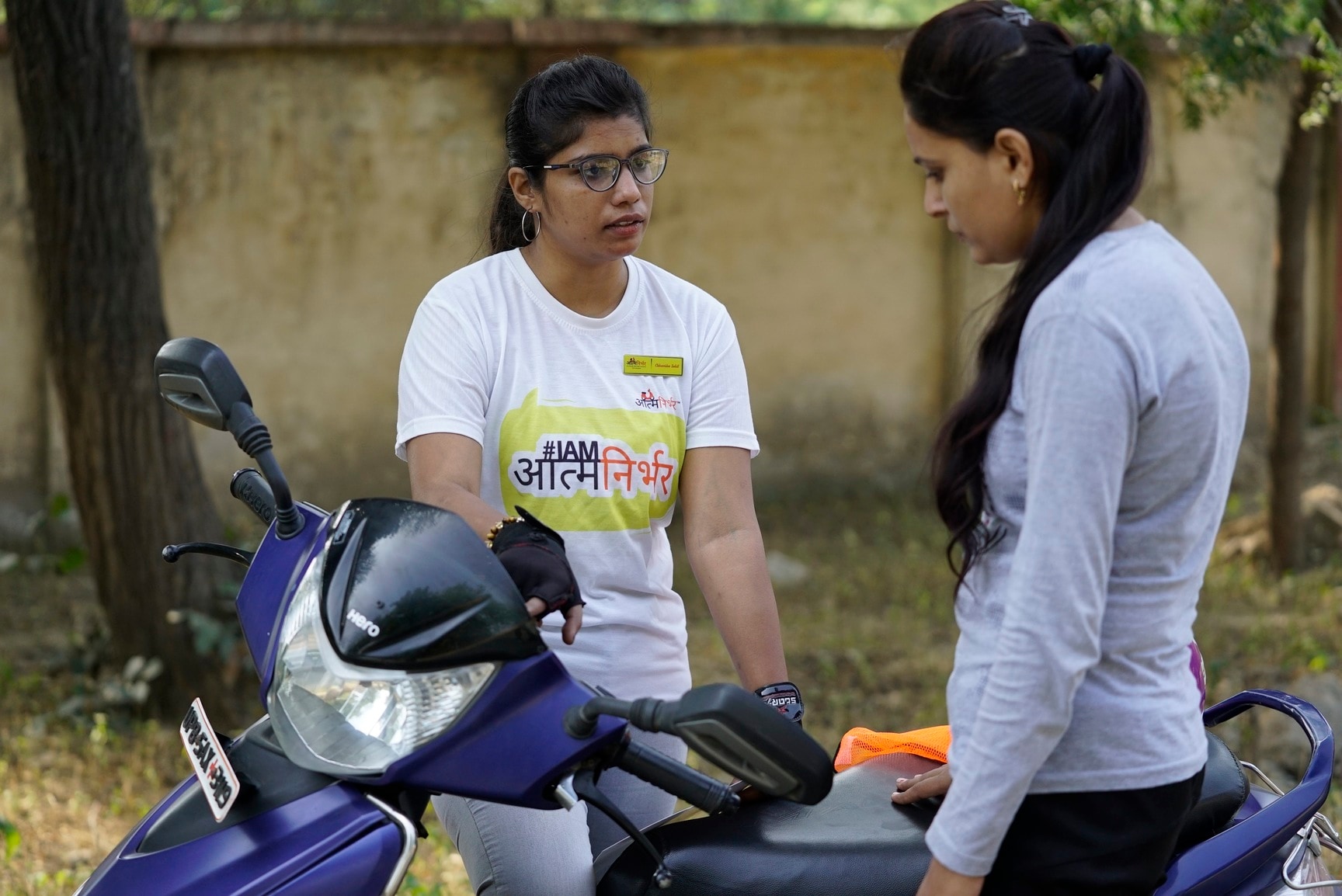 A professional female instructor teaching a student how to ride a scooty in Delhi.